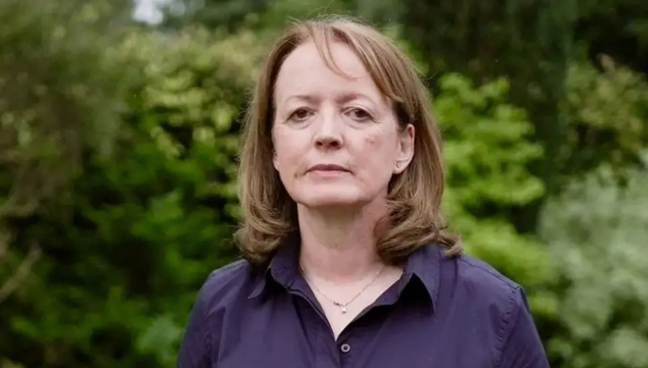 Dr Susan Gilby staring at the camera. She is wearing a purple blouse. 