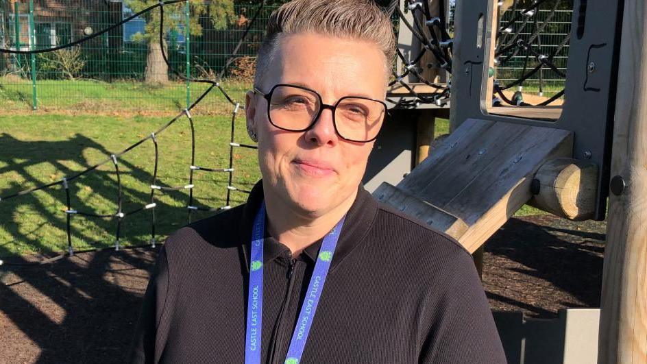 A female headteacher standing in front of a climbing frame in the school playground of Castle East Academy School.