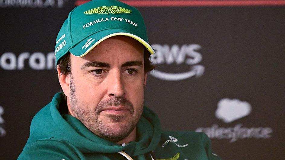 Fernando Alonso wearing an Aston Martin cap and hoodie at a news conference during Bahrain testing