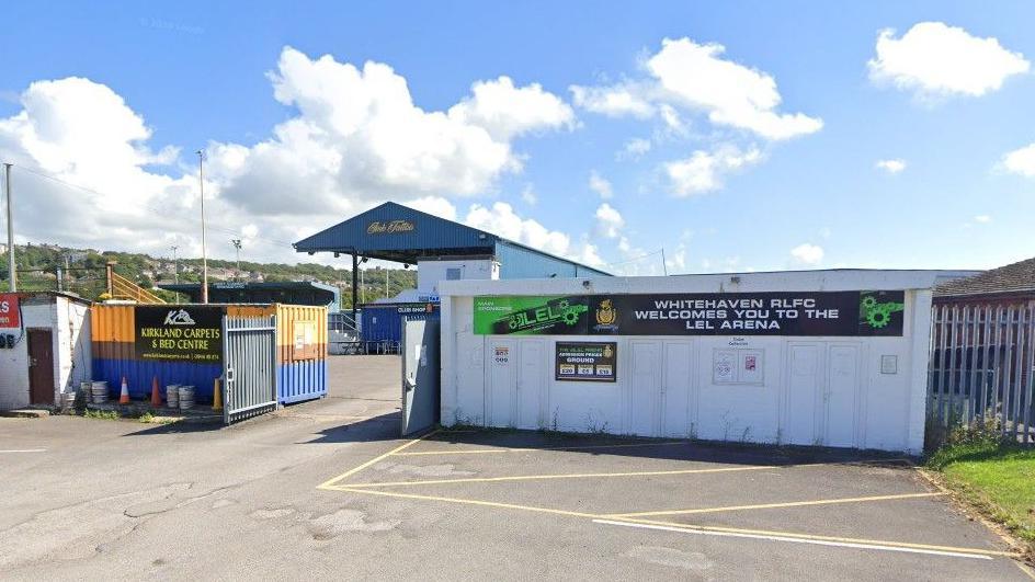 Photo of outside of Whitehaven RLFC with sign sayings "Welcome to the LEL Arena". Blue skies. 