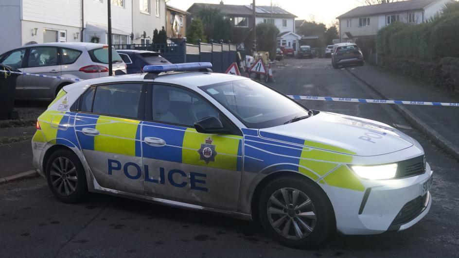 Police car and police tape near scene of blast on street