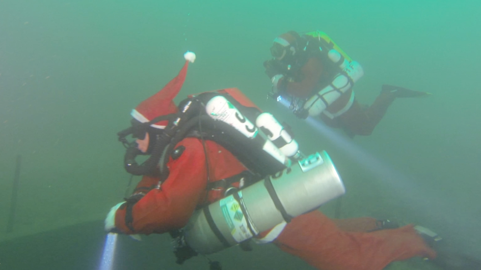 George in full scuba gear and a Santa costume, including a hat, underwater with a dive partner, also dressed as Santa