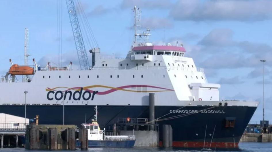 A blue and white Condor ferry in the dock on a cloudy day.