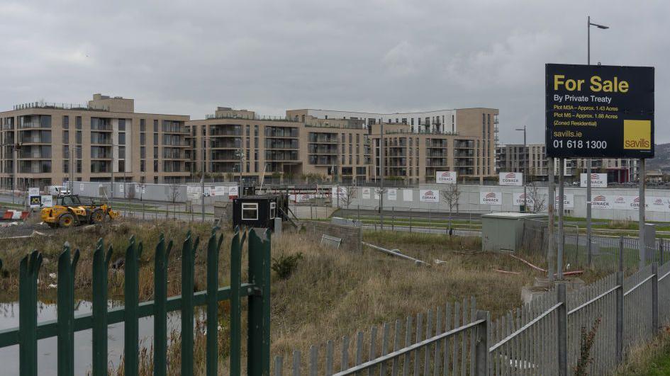 A construction site for a mixed-use development in Dublin, Ireland. A for sale sign is at the forefront