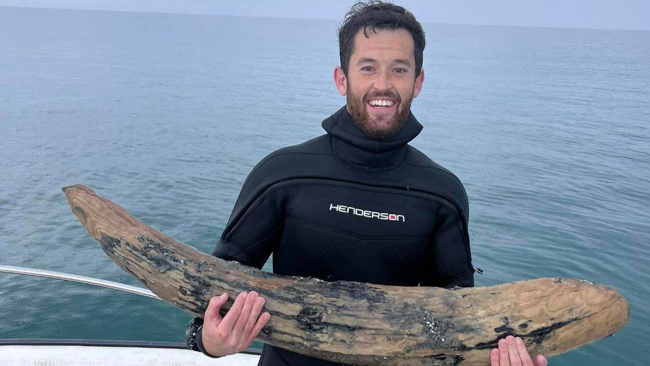 Alex Lundberg holds ancient mastodon tusk