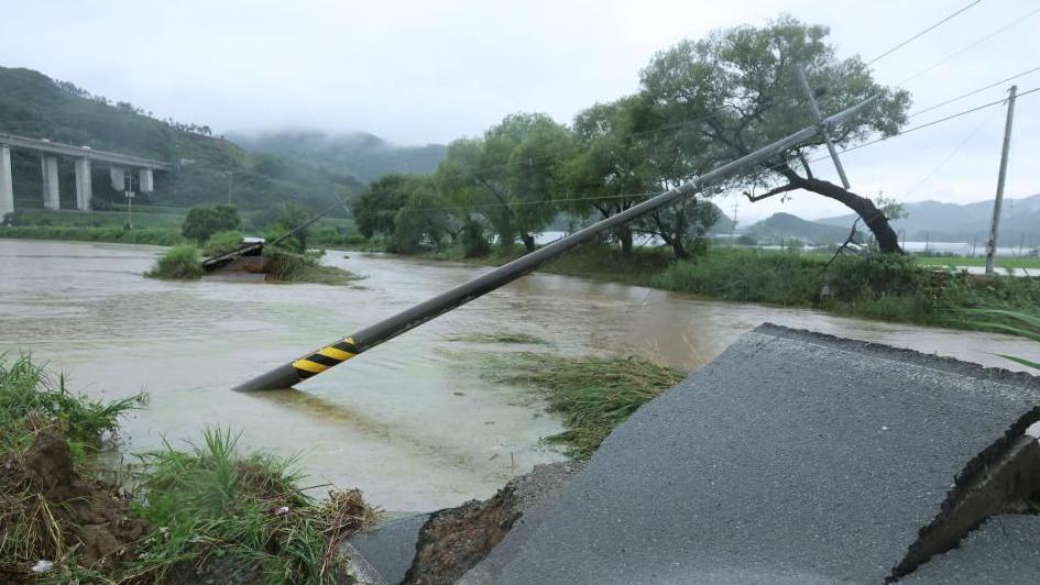 An electric pole leans over on a damaged road in Gongju, South Chungcheong Province, central South Korea, on 17 July