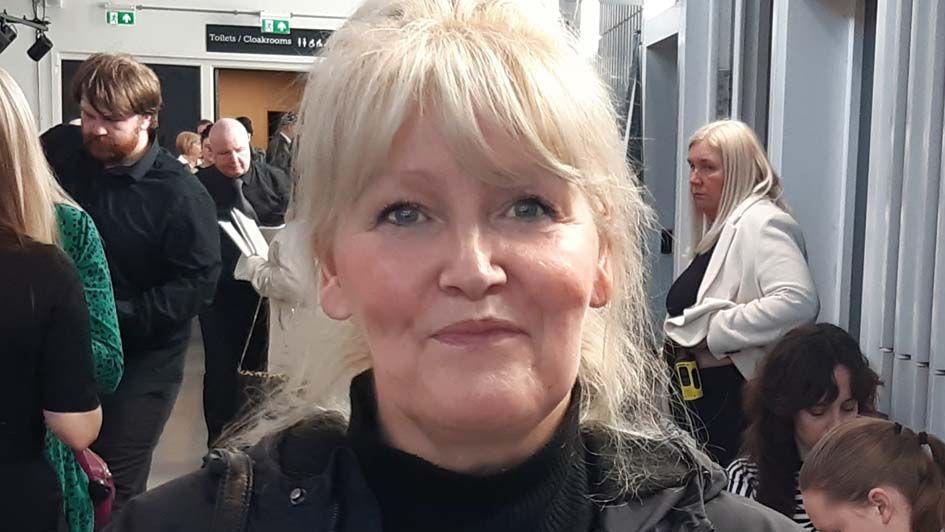 Head shot of Jane Podmore, she is smiling and has blonde hair tied up. She is in a room full of people at the jobs fair in Blackpool