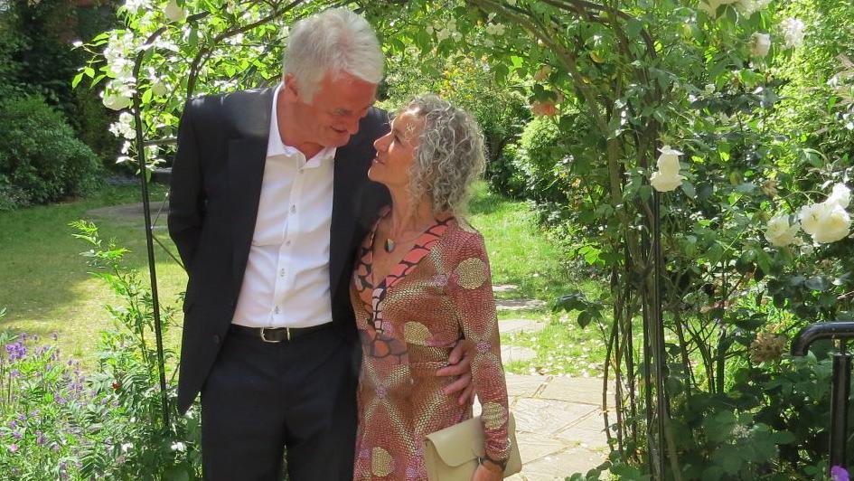 A couple standing in front of a garden arch
