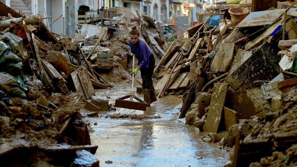 A woman trying to clear muddy water from a street in the town of Paiporta, south of the city of Valencia