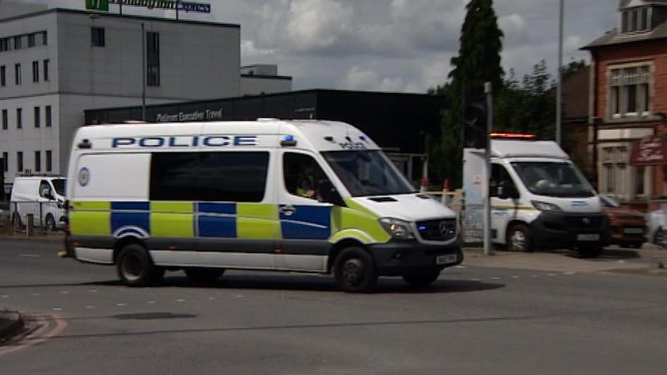 A police van crosses a road junction with other traffic in the background