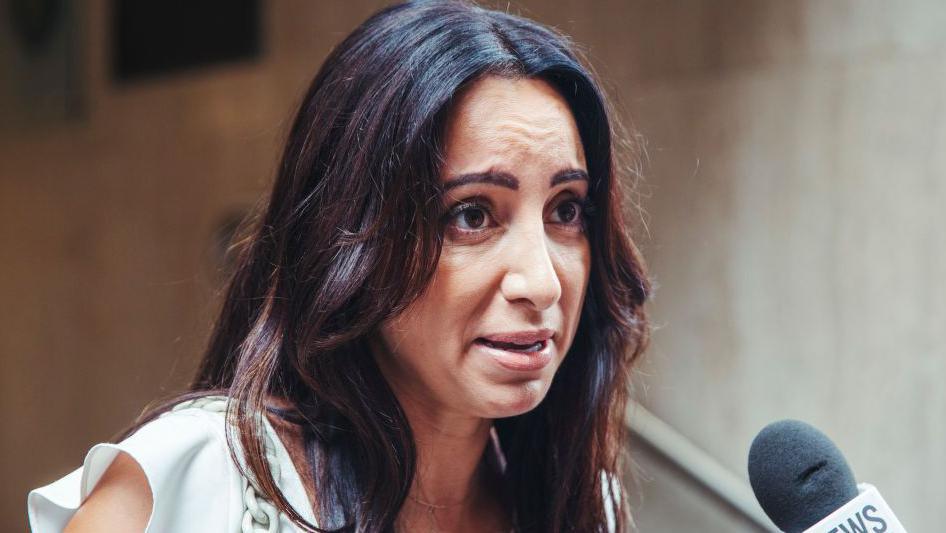 Antoinette Lattouf, wearing a white top, speaks into a microphone outside court