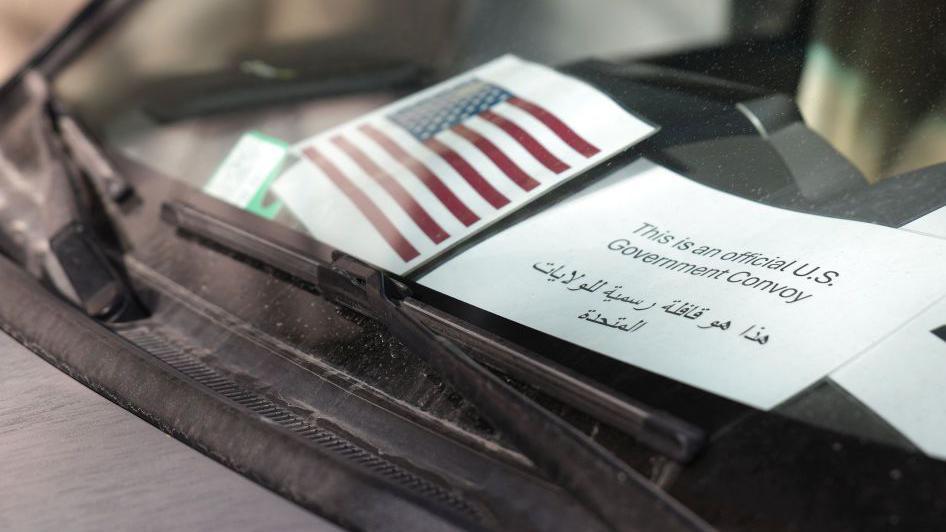 A car belonging to the US delegation parked outside a hotel in Damascus. On the dashboard a US flag and government sign is displayed