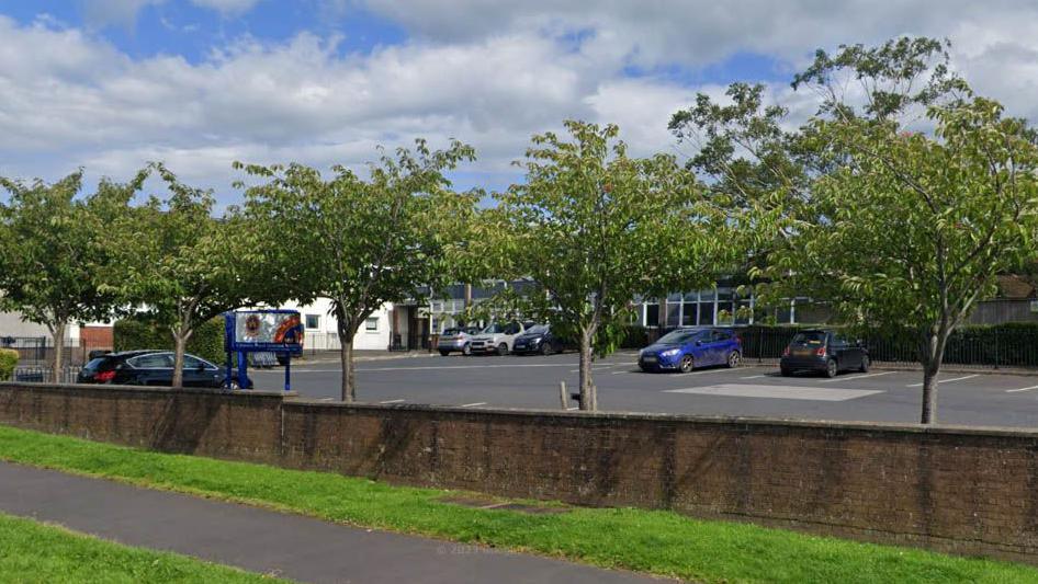 Street view image of Clitheroe Royal Grammar School showing the school building behind a car park lined with trees