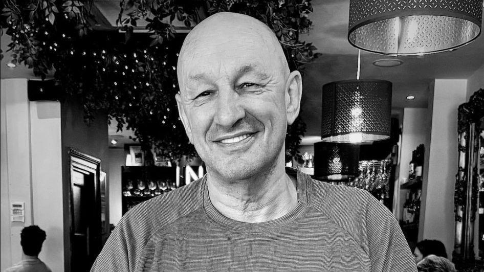 A black and white picture of Craig Noman smiling at a restaurant. 