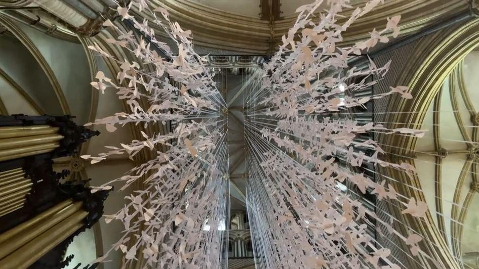 A view from the ground pointed up to the top of the nave with hundreds of white paper doves suspended from the top