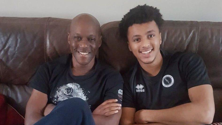 Joshua and dad David sitting on a living room sofa