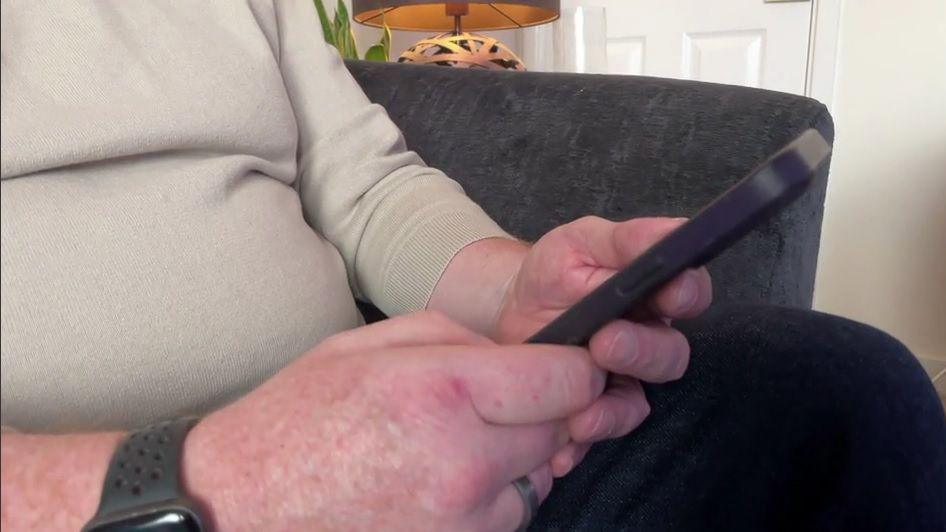 A close-up of a man holding a phone.