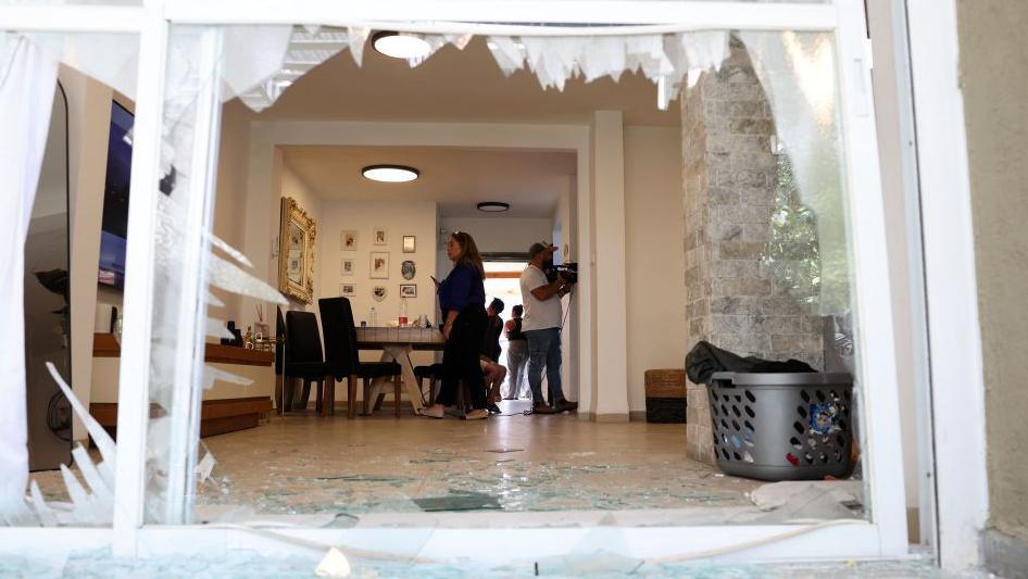 Residents check the damage caused by a rocket fired from Lebanon in the Israeli coastal town of Acre on August 25, 2024