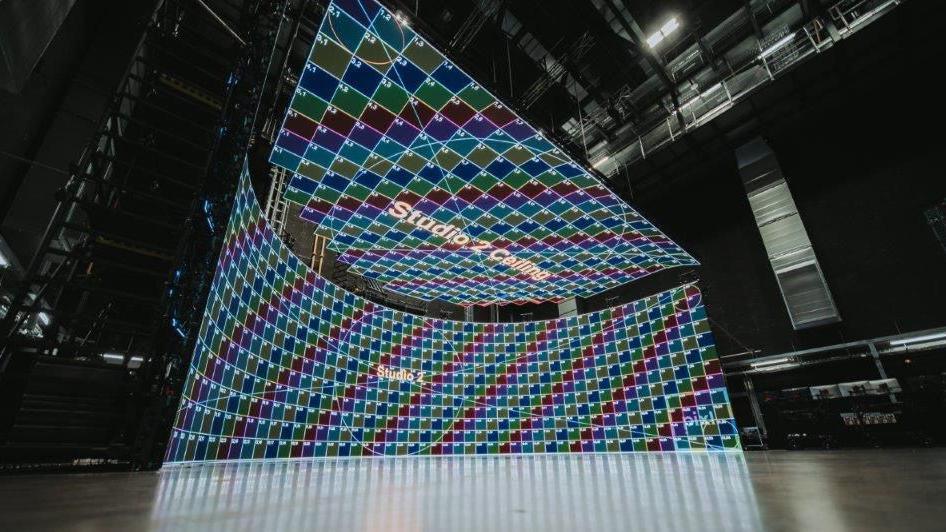 The studio space with a green screen made up of a series of of large multi-coloured grids.
