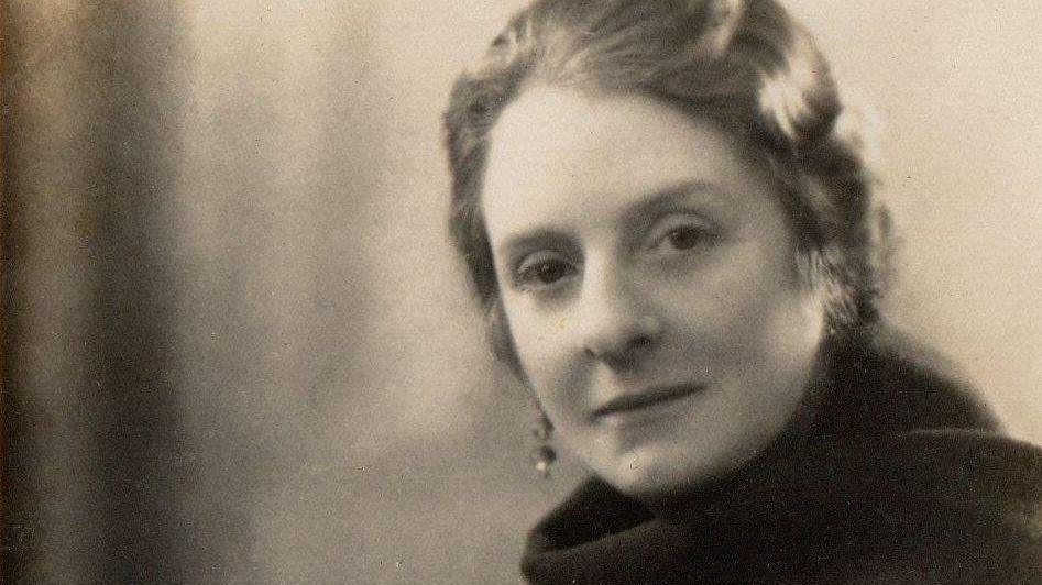 A sepia photograph of a woman with a scarf and earrings.