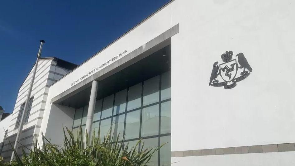 The white-walled, glass-fronted Isle of Man Courts of Justice building with a clear blue sky in the background.