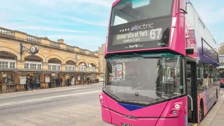 A pink bus parked outside York railway station