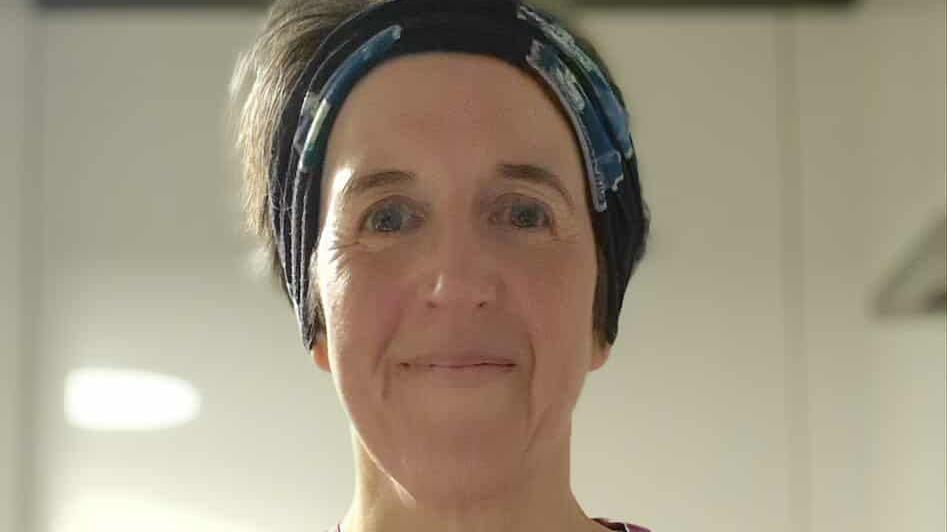 Jen Gray smiling at the camera. She is wearing a black headband. 