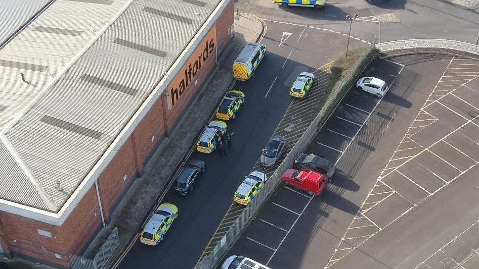 A drone shot of the police response, with cars parked either side of the road near the old Wickes building