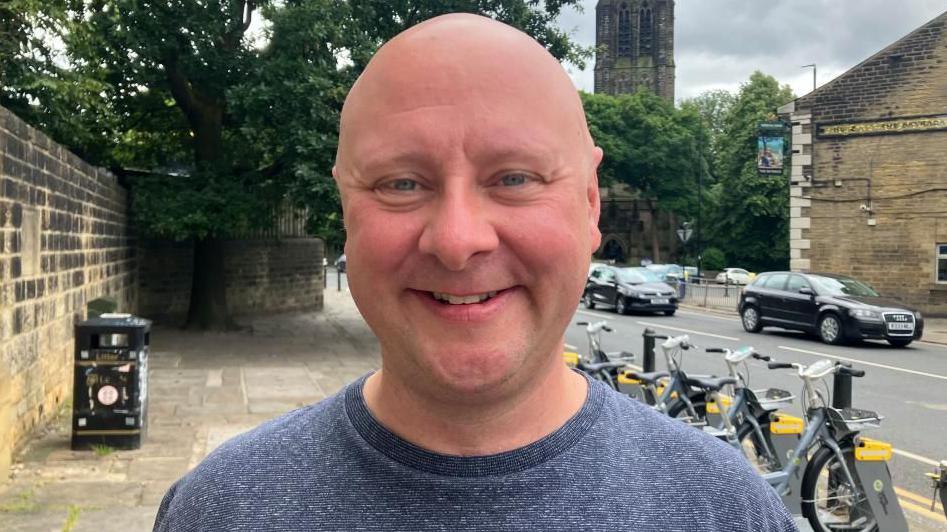 Cyclist Rick Webb by a bike docking station in Headingley