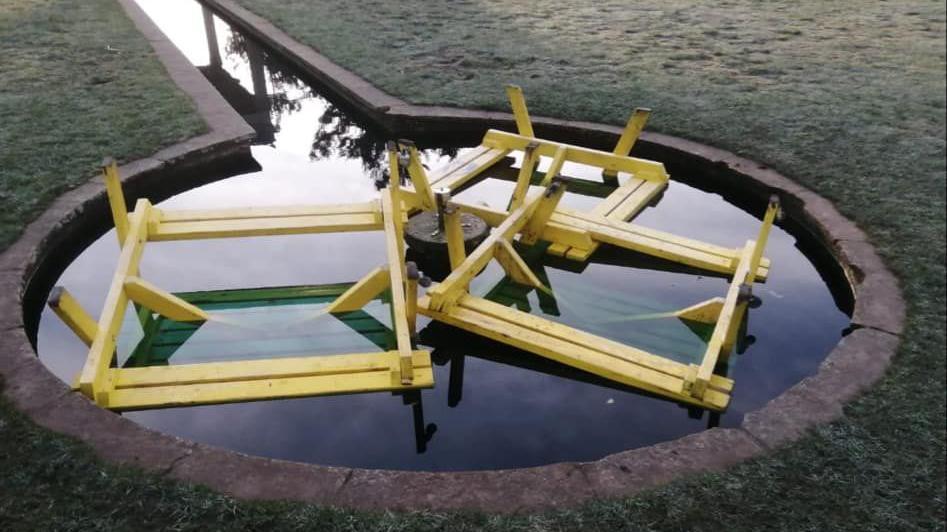 Three yellow benches upside down in a water fountain in the park.