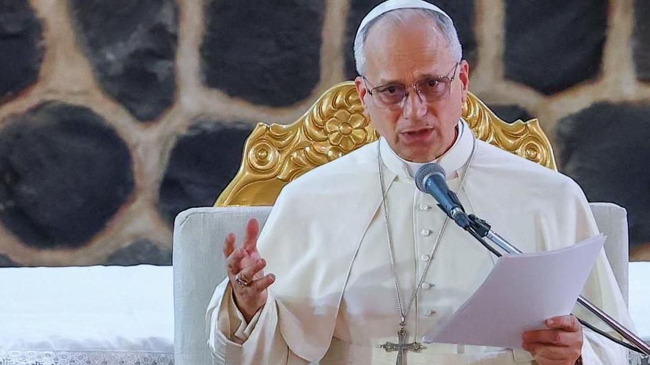 Pope Leo speaks at a podium.