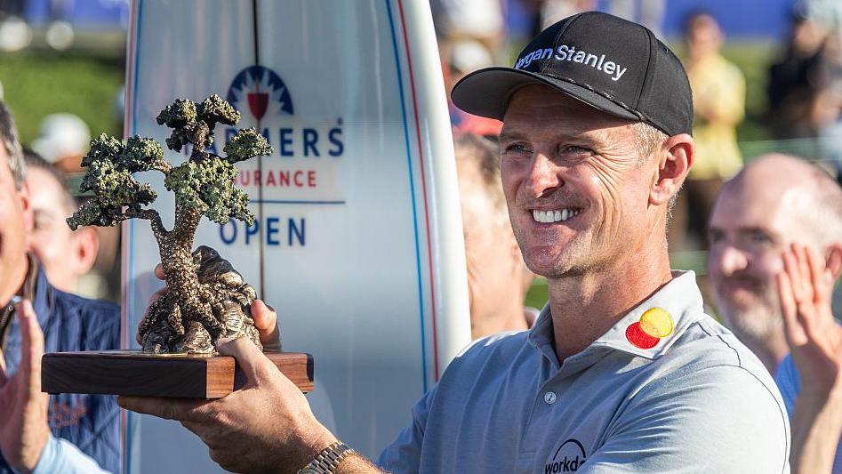 Justin Rose is presented the Championship trophy after winning the Farmers Insurance Open