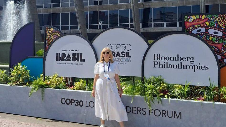 Image shows the Mayor wearing a white sundress with sun glasses on.
She is standing in front of white banners which say 'COP30' and 'Bloomberg Philanthropies'.