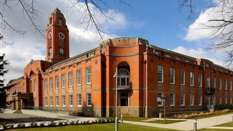 A view of red brick Trafford Town Hall with lawns and shrubs surrounding it