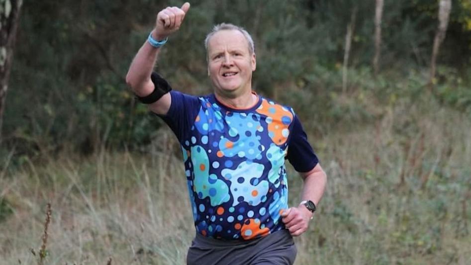 Ian Jones yn codi bawd wrth redeg ar y llwybr