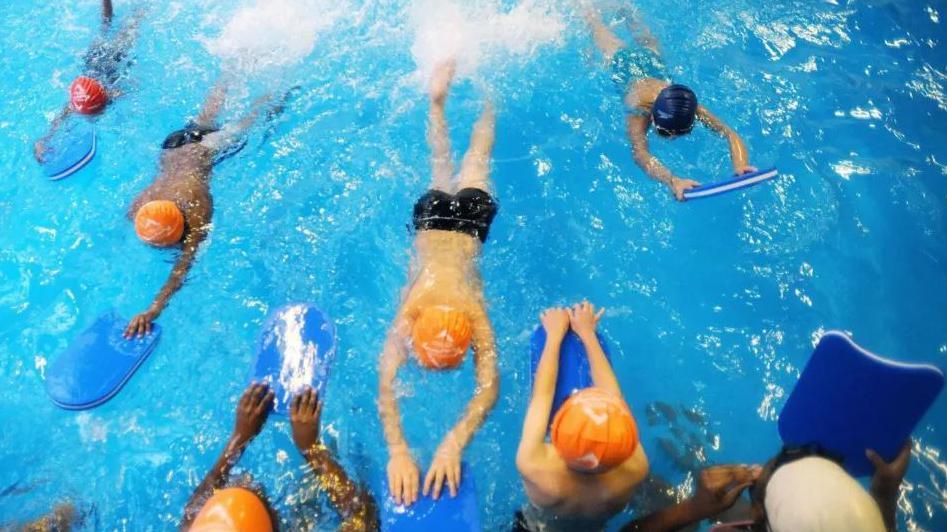 Children swimming in a pool using floats