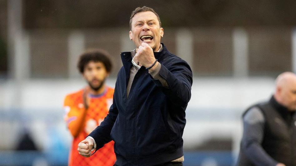 Duncan Ferguson shaking his fist in celebration. Two people are standing behind him.