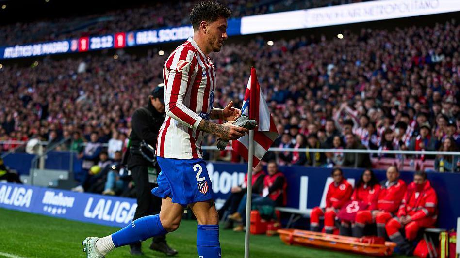 Jose Gimenez of Atletico Madrid takes a pigeon of the pitch during the La Liga match between Atletico de Madrid and Real Sociedad 