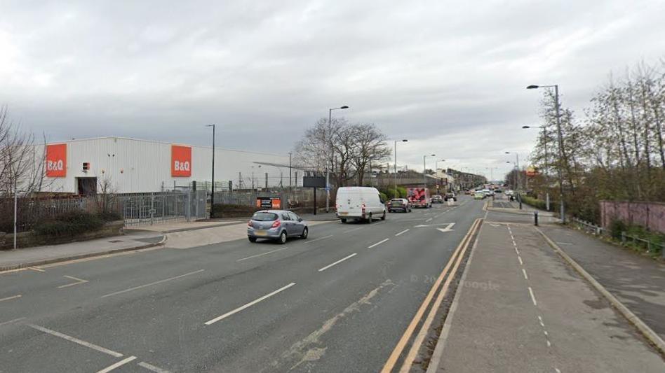 The image shows the road running along retail stores and fast food restaurants.