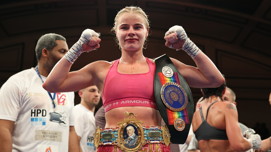 Tysie Gallagher celebrates with belts around her waist and on her shoulder