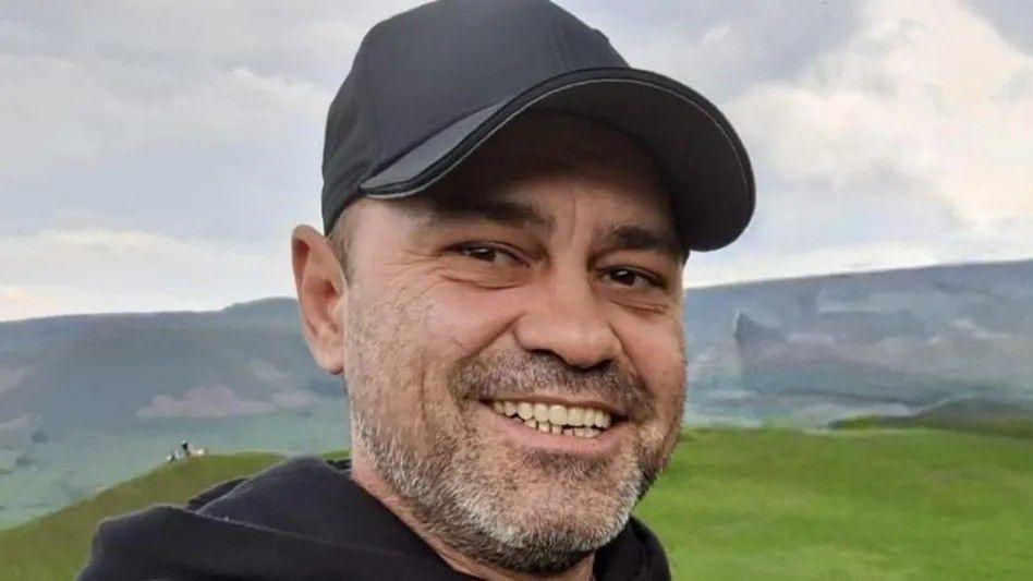 Claudiu-Carol Kondor, a gentleman in his early 40s with grey stubble and a baseball cap. He is pictured against the backdrop of some hills