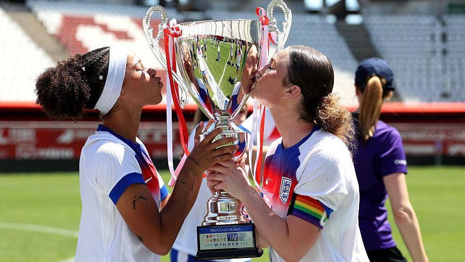 Lenna Gunning-Williams and captain Ruby Mace kiss the trophy