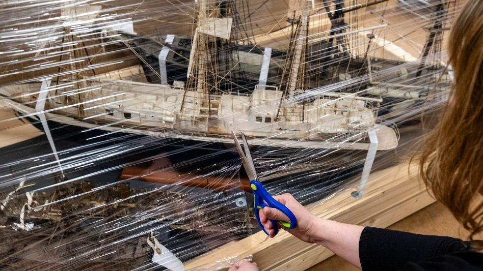 A woman packaging up one of the model ships being moved