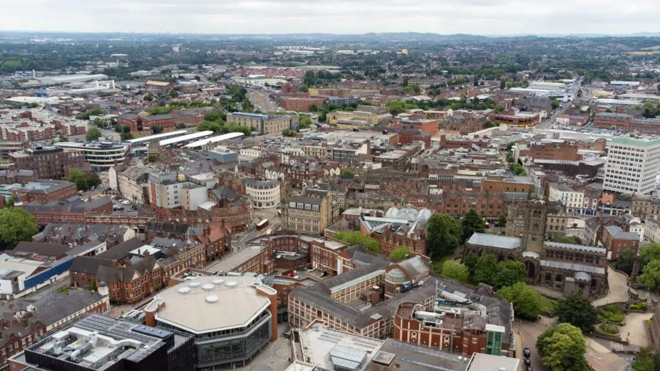 An aerial view of the city of Wolverhampton showing numerous buildings and some city routes.