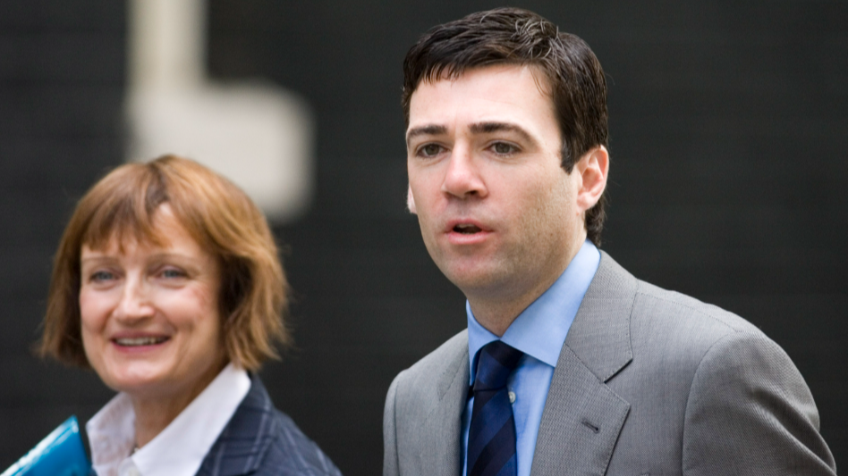 Tessa Jowell (left) has chin-length light brown hair and wears a white shirt and navy checked suit jack. Andy Burnham (right) has dark short hair and wears a grey suit with a blue shirt and navy-blue striped tie.