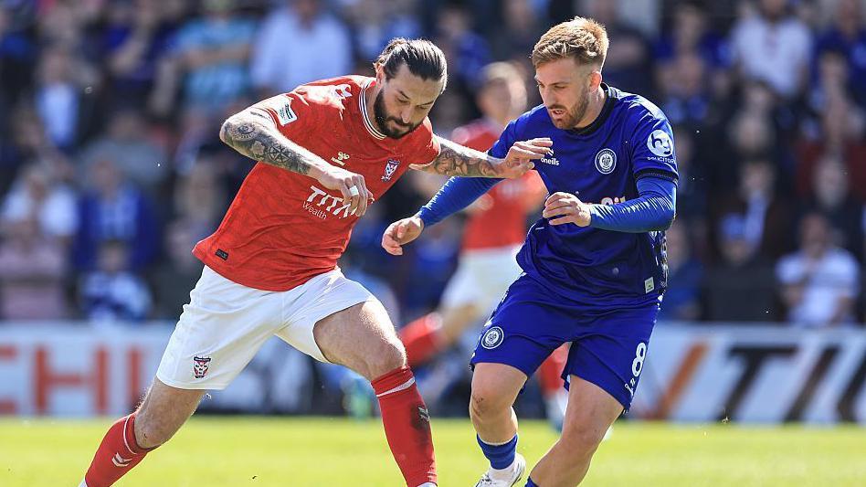 York City's Oliver Banks (left) challenges for the ball with Rochdale's Harvey Gilmour during their match in the National League on 25 April.