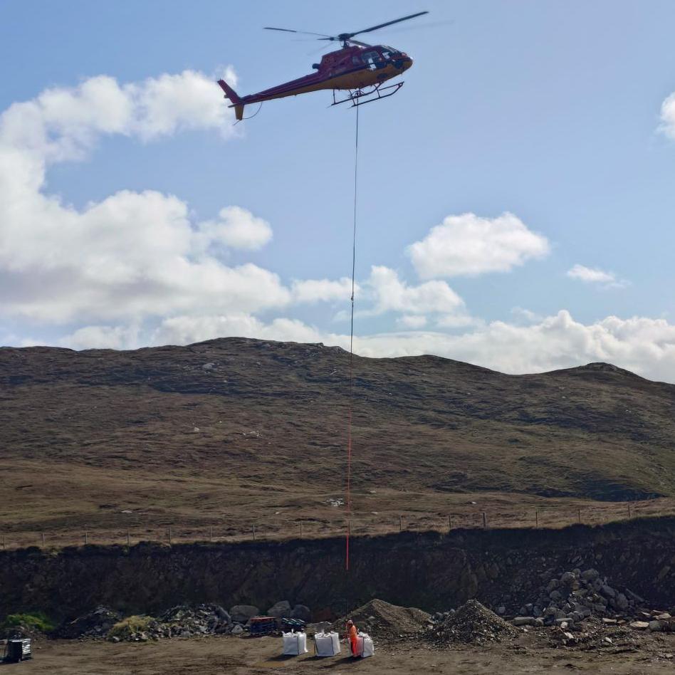 A helicopter being attached to bags of construction material