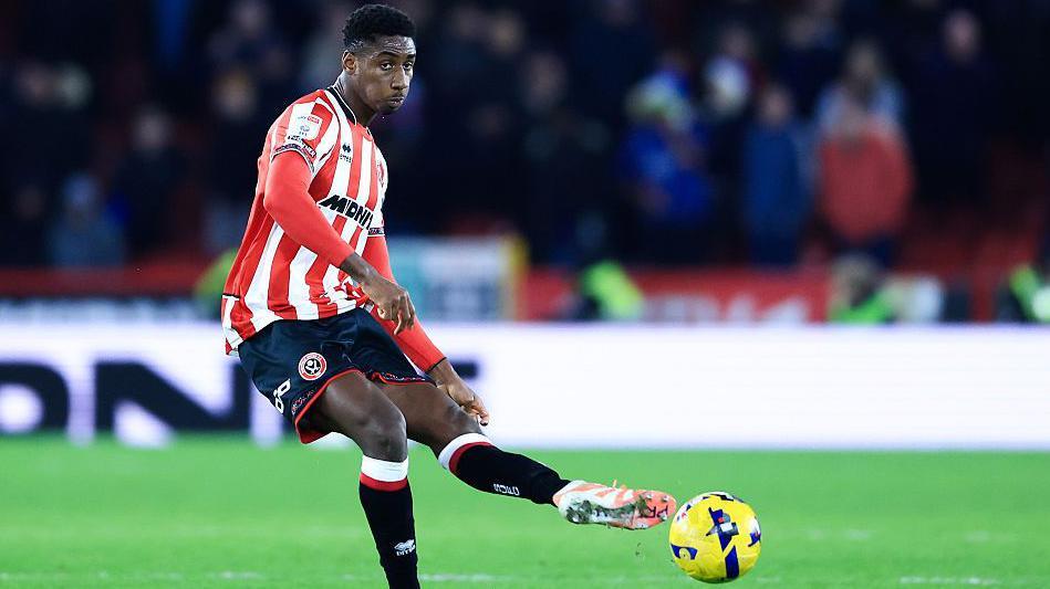 Djibril Soumare, in the red and white stripes of Sheffield United, plays the ball forward with his left foot.