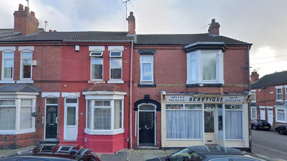 A row of terraced houses. The one at the very end features a sign that reads "Beautique".