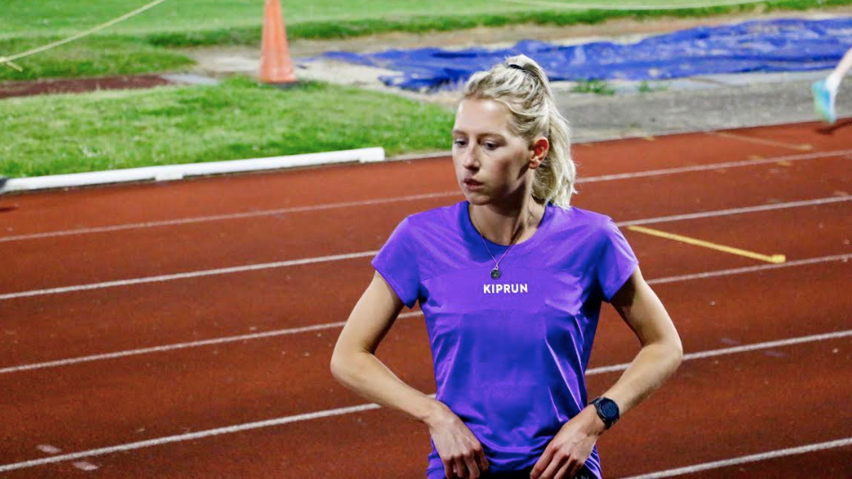 Kate Axford stands next to an athletics track during a training session